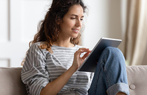 Woman sitting on sofa looking at iPad