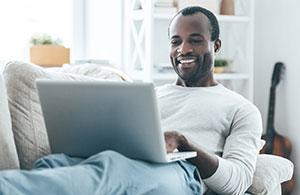 Man sitting on sofa looking at laptop