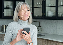 Woman holding cell phone in kitchen